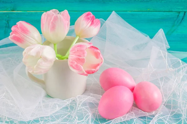Roze paaseieren en tulpen in een vaas op witte stof en blauwe houten achtergrond. Rechtenvrije Stockafbeeldingen