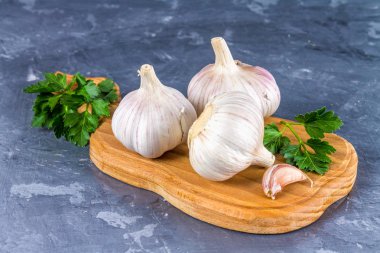 Diş sarımsak ve sarımsak ampul ahşap bir tahta üzerinde gri bir arka plan üzerinde.