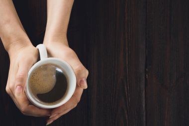 Ahşap masa üzerinde kahve holding kadın eller