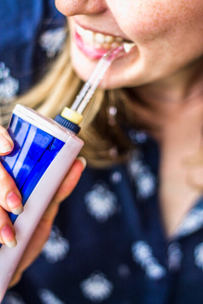 A woman using an oral irrigator in bathroom