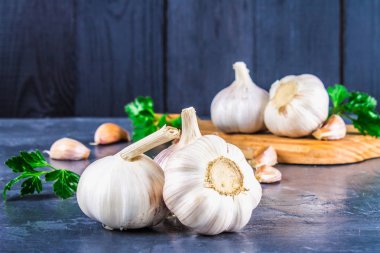 Diş sarımsak ve sarımsak ampul ahşap bir tahta üzerinde gri bir arka plan üzerinde.