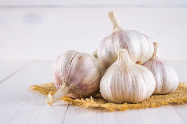 Garlic cloves and garlic bulb on a white wooden table — Stock Photo, Image