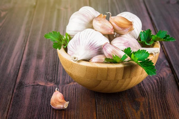 Garlic cloves and garlic bulb in a wooden bowl.