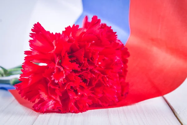 Carnation and ribbon of St. George, as a symbol of victory against the background of the Russian flag. May 9, the day of victory.