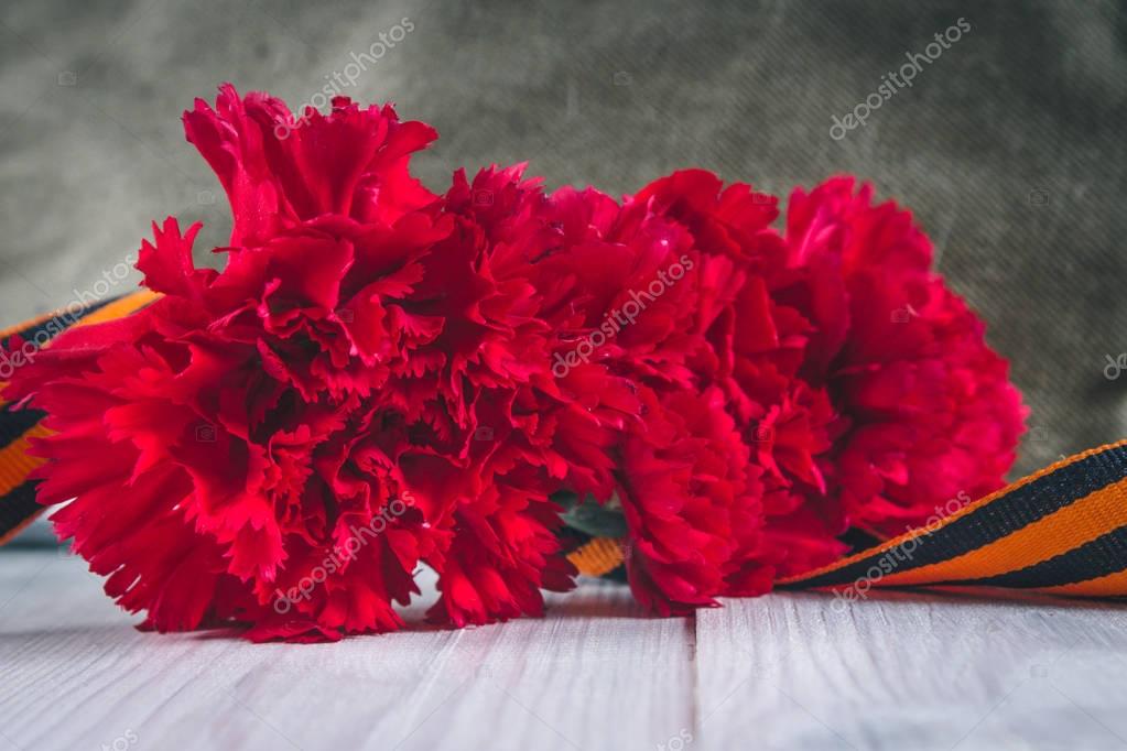 Flores de clavel, cinta George y gorra de guarnición militar con una estrella  roja. 9 de mayo Día de la Victoria 2023