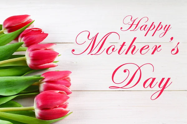 Boldog anyák napja szöveg fehér rusztikus fa alapon rózsaszín tulipánok jelentkezik. üdvözlés kártya fogalom. érzéki pályázati nők kép. tavaszi virágok lapos feküdt — Stock Fotó