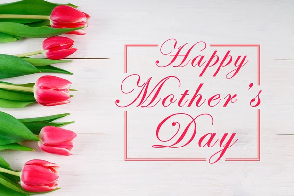 Happy mother's day text sign on pink tulips on white rustic wooden background. greeting card concept. sensual tender women image. spring flowers flat lay — Stock Photo, Image