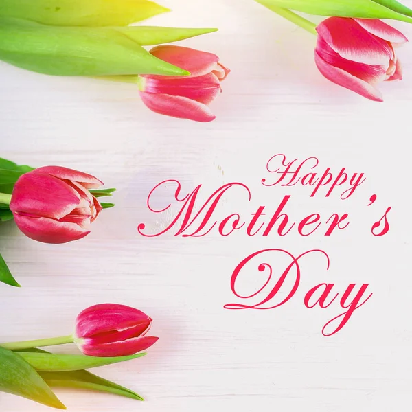 Signo de texto del día de la madre feliz en tulipanes rosados sobre fondo de madera rústico blanco. concepto de tarjeta de felicitación. sensual mujer tierna imagen. flores de primavera plano laico —  Fotos de Stock
