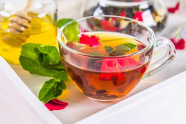 Çiçek çay bir fincan, bir kavanoz bal, çay beyaz bir tepsi yatakta bir kavanoz içinde.