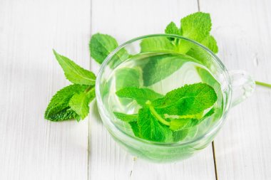 Beyaz ahşap bir masa üzerinde bir fincan nane çayı. Üstten Görünüm