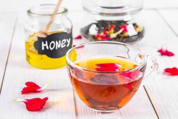 Çiçek siyah çay, bal olabilir, bir beyaz tahta masada yaprakları.