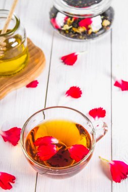 Bir fincan çay, bal konservesi ve siyah bir bitki çiçek çayı Beyaz ahşap bir masa üzerinde bir küptür. Üstten Görünüm.