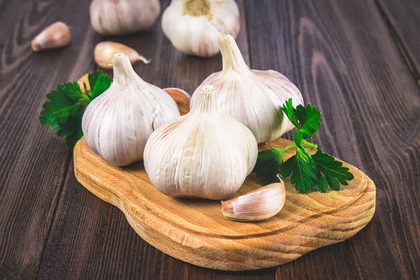 Top view, flat lay. Garlic clove and garlic bulb on a brown wooden table. — Stock Photo, Image