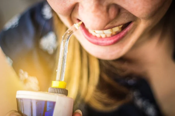 A woman using an oral irrigator in bathroom. Selective focus — Stock Photo, Image