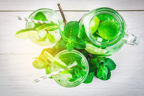 Mojito com hortelã e limão em um copo e um jarro com tubos. Branco — Fotografia de Stock