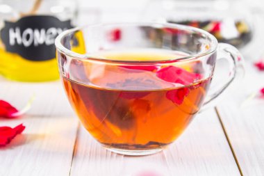 Çiçek siyah çay, bal olabilir, bir beyaz tahta masada yaprakları.