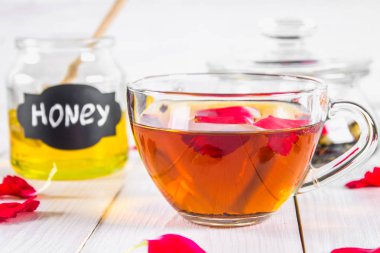 Çiçek siyah çay, bal olabilir, bir beyaz tahta masada yaprakları.