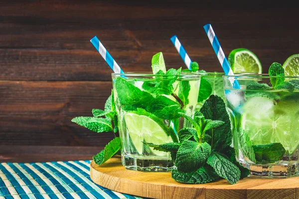 Mojito con menta y lima en un vaso y una jarra en el jabalí redondo —  Fotos de Stock