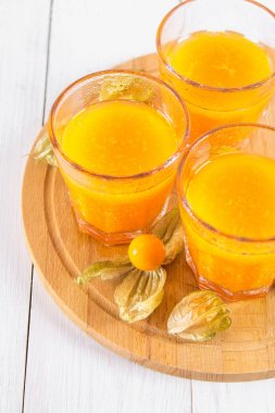 Physalis Beyaz ahşap bir masa üzerinde yapılmış bir Portakallı gazoz.