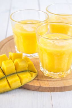 Sarı yüzlü mango, muz ve portakal bir beyaz tahta üzerinde ta