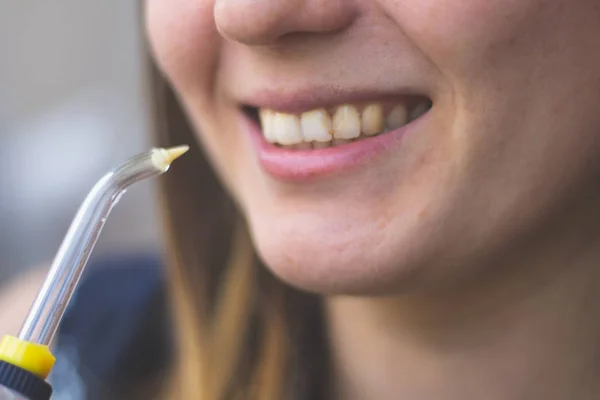 A woman using an oral irrigator in bathroom — Stock Photo, Image