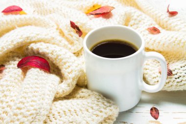 Örme bir eşarp ile ahşap bir masa üzerinde sonbahar ortamda sıcak kahve bir fincan kazak. Konfor, sıcaklık, rahat.