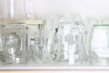 Farklı cam raf üzerinde beyaz bir dolaba. Bankalar, sürahi, bardak, bardak.