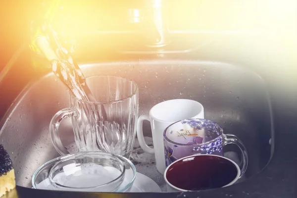 Dirty dishes in foam in the sink waiting for washing. Mugs, plates, cutlery. — Stock Photo, Image