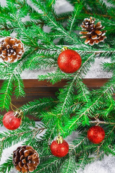 Bolas de Natal vermelho e cones estão em uma prateleira marrom de madeira cercada por ramos de abeto . — Fotografia de Stock