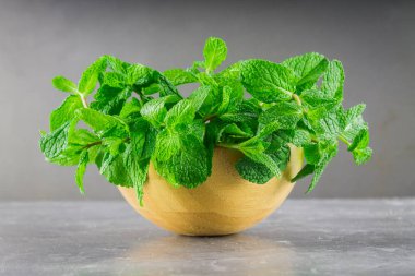 Yeşil nane gri bir arka plan üzerinde bir ahşap kase