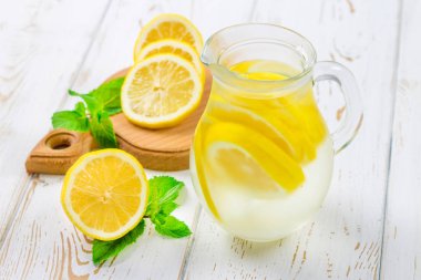 Bir sürahi soğuk limonata limon tarafından çevrili beyaz ahşap zemin üzerinde ile.