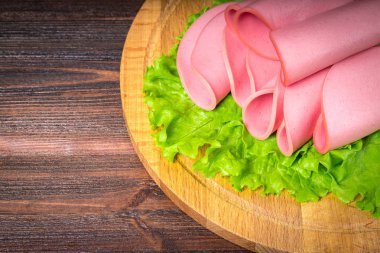 Sosis salata ile bir yuvarlak ahşap tahta üzerine dilimlenmiş.  