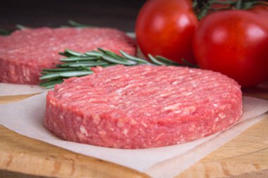 Biberiye ve domates ile parşömen kağıt üzerinde ham burger. Woode