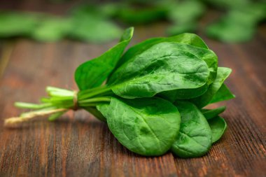 Taze sulu ıspanak ahşap bir kahverengi masa üzerinde bırakır. Doğal ürünler, Yeşiller, sağlıklı gıda, vitaminler.