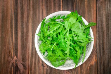 Taze sulu roka yaprakları kahverengi ahşap bir masa üzerinde.