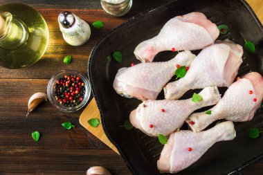 Ahşap bir masa üzerinde bir tavada çiğ tavuk budu. Et yemek pişirmek için malzemeler. Üstten Görünüm.