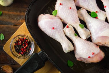 Ahşap bir masa üzerinde bir tavada çiğ tavuk budu. Et yemek pişirmek için malzemeler. Üstten Görünüm.