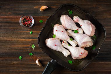 Ahşap bir masa üzerinde bir tavada çiğ tavuk budu. Et yemek pişirmek için malzemeler. Üstten Görünüm.