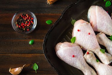 Ahşap bir masa üzerinde bir tavada çiğ tavuk budu. Et yemek pişirmek için malzemeler. Üstten Görünüm.