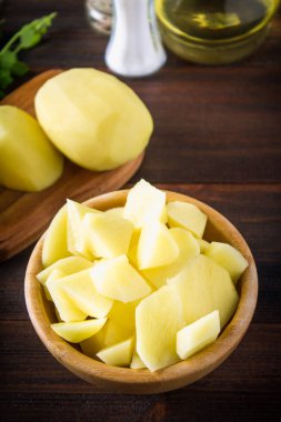 RAW soyulmuş ve dilimlenmiş patates üzerinde eski yıpranmış ahşap masa