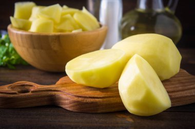 RAW soyulmuş ve dilimlenmiş patates üzerinde eski yıpranmış ahşap masa