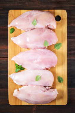 Çiğ tavuk fileto kesme tahtası ahşap bir masa arka planı. Et yemek pişirmek için malzemeler. Bir yazıt için boş yer. Uzay kopyalayın. Düz lei. Üstten Görünüm.