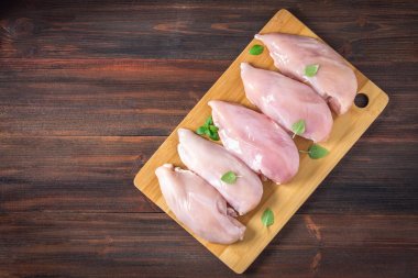 Çiğ tavuk fileto kesme tahtası ahşap bir masa arka planı. Et yemek pişirmek için malzemeler. Bir yazıt için boş yer. Uzay kopyalayın. Düz lei. Üstten Görünüm.