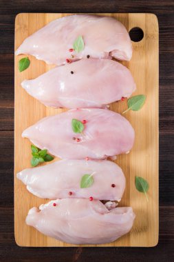 Çiğ tavuk fileto kesme tahtası ahşap bir masa arka planı. Et yemek pişirmek için malzemeler. Bir yazıt için boş yer. Uzay kopyalayın. Düz lei. Üstten Görünüm.