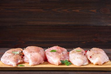 Çiğ tavuk fileto kesme tahtası ahşap bir masa arka planı. Et yemek pişirmek için malzemeler. Bir yazıt için boş yer. Kopyalama alanı.