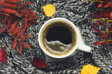 Örme bir eşarp ile ahşap bir masa üzerinde sonbahar ortamda sıcak kahve bir fincan kazak. Konfor, sıcaklık, rahat.