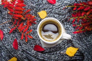 Örme bir eşarp ile ahşap bir masa üzerinde sonbahar ortamda sıcak kahve bir fincan kazak. Konfor, sıcaklık, rahat.