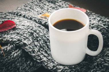 Örme bir eşarp ile ahşap bir masa üzerinde sonbahar ortamda sıcak kahve bir fincan kazak. Konfor, sıcaklık, rahat.