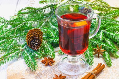 Yeni yıl mulled şarap bir bardak içinde arka planda twigs, mumlar ve çelenk.