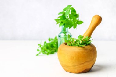 Hafif bir arka plan üzerinde ahşap bir harç yeşil limon fesleğen. Fesleğen şişe.